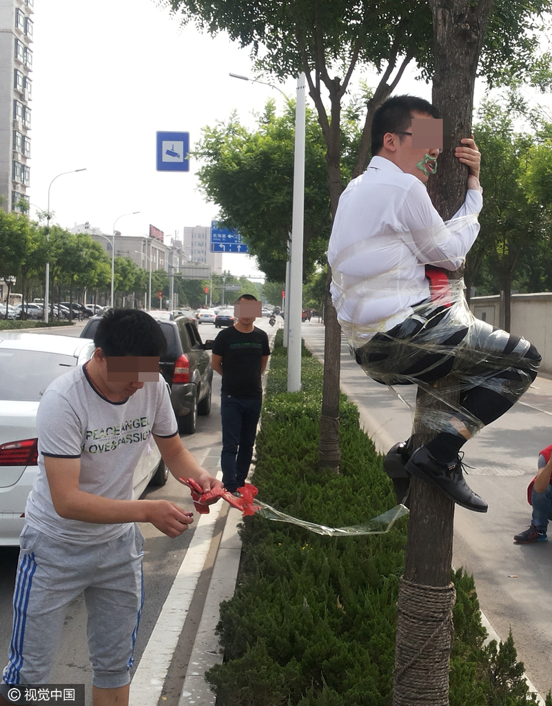 在山东淄博周村区马路上,惊现"奇葩"婚俗,一位新郎被人用胶带捆绑在