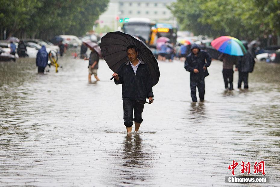 　　9月25日，南京城东银城东苑门口的道路上，市民在积水中涉水而行。持续的暴雨导致南京城不少路段严重积水，给市民的出行造成极大的影响。泱波摄