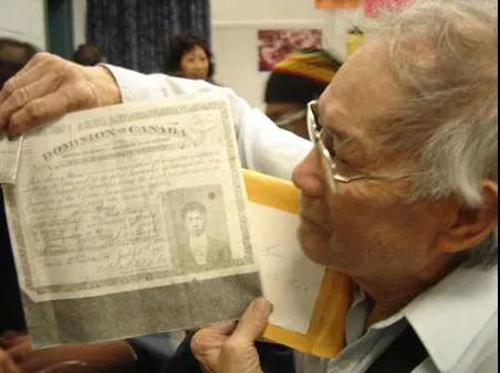 加拿大华人手持其父1918年缴纳完“人头税”后获得的移民书证。 加拿大华人手持其父1918年缴纳完“人头税”后获得的移民书证。