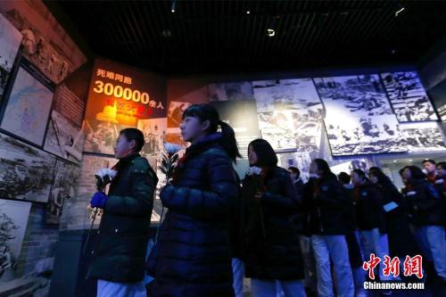 12月13日，中国人民抗日战争纪念馆举办“丹青映史——侵华日军南京大屠杀遇难同胞80周年祭艺术作品特展”。图为学生观看展览。 中新社记者 富田 摄