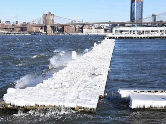 1月5日,大风吹卷着河水拍打着美国纽约市布鲁克林东河一座码头,码头上覆盖着厚厚的冻冰。(新华/法新)